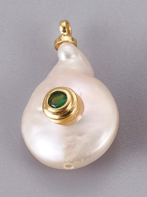 A bezeled emerald pearl charm featuring a white baroque pearl set with a green gemstone in a gold-tone bezel.