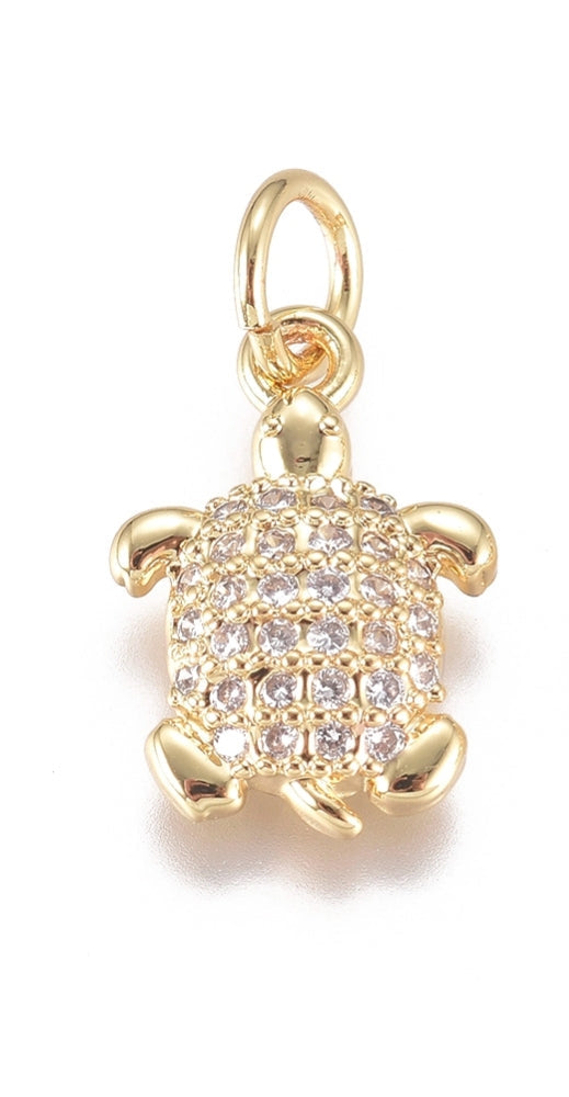 Gold-tone charm in the shape of a turtle with a shell paved in clear stones and a polished metal bail.
