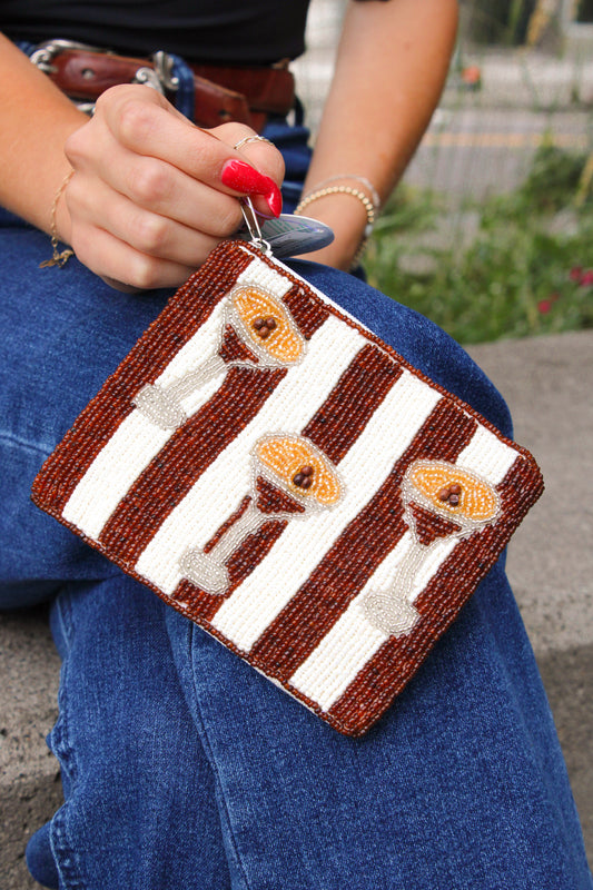 A striped beaded bag with espresso martini glass designs, held by a model in blue jeans.
