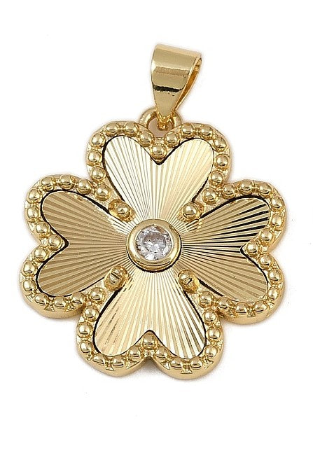 A gold clover charm featuring textured radiating petals, a beaded border, and a central clear stone.