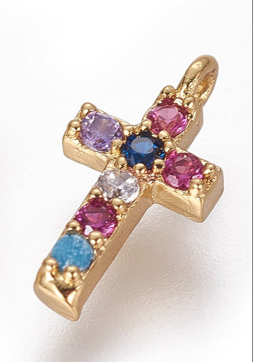 Gold-tone charm in a rainbow cross design, decorated with small, colorful round stones on a white background.
