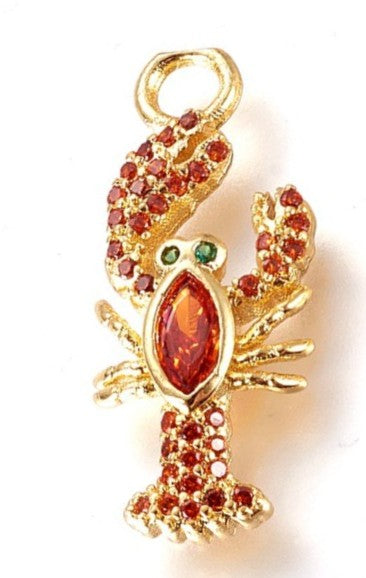 Gold lobster charm featuring red pave-set stones, a marquise-cut red center stone, and tiny green crystal eyes.