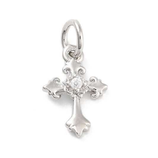 Silver cross charm featuring ornate fleur-de-lis ends and a small clear gemstone at its center.